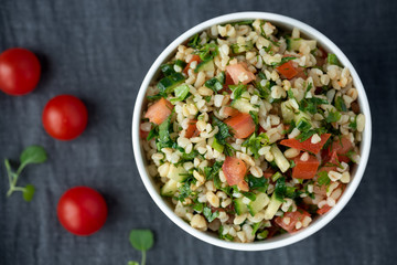Oriental salad tabbouleh from bulgur, parsley and tomatoes in a white  bowl.