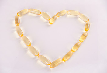 Capsules of heart shaped fish oil Omega 3 or Vitamin E. Vitamins for health promotion.