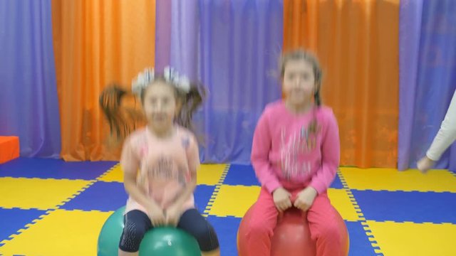 Children's playroom. Studio entertainment for young children. Little girls jump on the gymnastic balls.