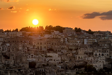 Fototapeta premium Amazing view while Sun is setting down above the famous tourist destination ancient beautiful town of Matera, the Sassi di Matera, Basilicata, Southern Italy, warm scenery summer evening