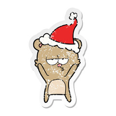 bored bear distressed sticker cartoon of a wearing santa hat