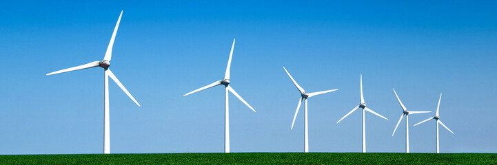 Panorama of wind turbines aligned in a green field