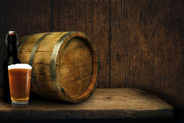 Wooden barrel and glass of beer on a old oak table of wood.