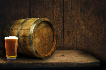 Wooden barrel and glass of beer on a old oak table of wood.
