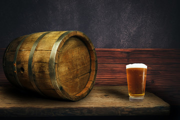 Wooden barrel and glass of beer on a old oak table of wood.