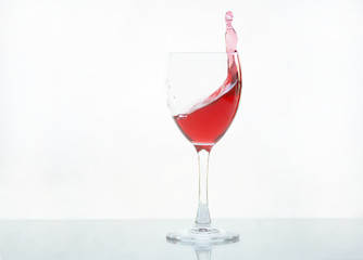 Red wine pouring in glass goblet isolated on white background