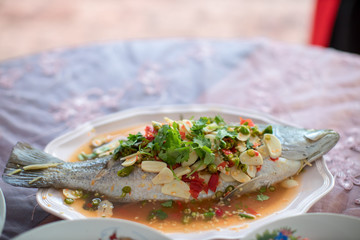 Steamed sea bass fish with lemon, Thai famous local food served on fish shape plate. Thai recommend menu for tourist. Steamed fish with herb and lemon, topped with spicy sour sauce. PLA NERNG MANAW.