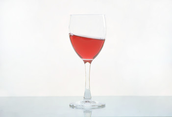 Red wine pouring in glass goblet isolated on white background