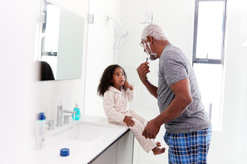 Grandfather Wearing Pajamas In Bathroom Shaving Whilst Granddaughter Watches