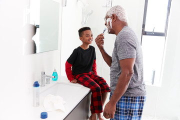 Fototapeta premium Grandfather Wearing Pajamas In Bathroom Shaving Whilst Grandson Watches