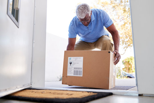 Senior Man Coming Back To Home Delivery In Cardboard Box Outside Front Door