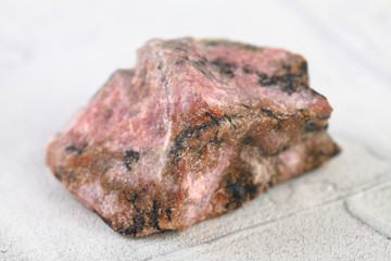 Natural mineral rock specimen - rough rhodonite stone from M. Sidelnikovo, Ural, Russia on white...
