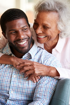 Smiling Senior Mother Hugging Adult Son At Home