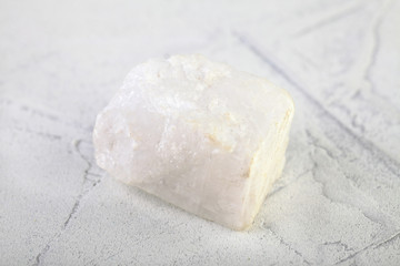 Raw Blue Calcite from Slyudyanka, Baikal, Russia on white cement background.