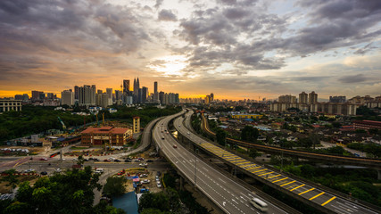 Fototapeta na wymiar Kuala Lumpur city skyline during dramatic sunset with elevated highway leading into the city.