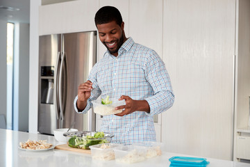 Man In Kitchen Preparing High Protein Meal And Putting Portions Into Plastic Containers