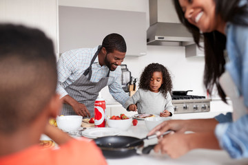 Family In Kitchen At Home Making Pancakes Together