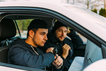 Thieves parked in an ally waiting while observing their target and loading their guns.