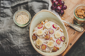 Healthy oatmeal bowl with banana, grapes and nuts. Breakfast or dessert idea, top view flat lay
