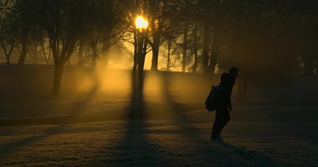 A Golfer walks between holes at sunrise.
