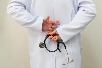 white coat male with  finger crossed left hand behind the back and a stethoscope in right hand