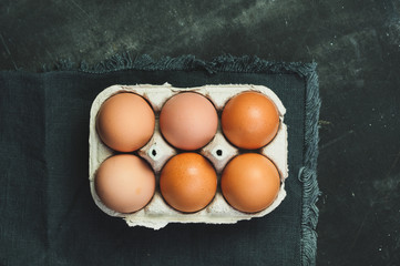 Brown eggs in box, dark background, top view flat lay