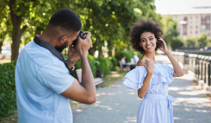 Young man taking photo of beautiful woman in park