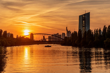 Europäische Zentralbank mit Frankfurter Skyline im Sonnenuntergang