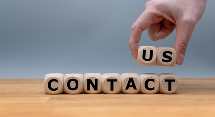 Dice form the word "CONTACT US" while a hand rises the letters "US".