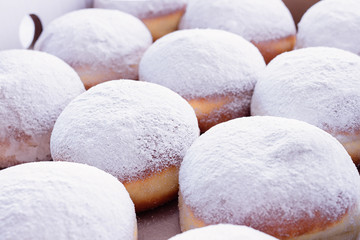 Fototapeta na wymiar Jelly filled doughnuts with powdered sugar on a bed with white sheets
