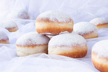 Jelly filled doughnuts with powdered sugar on a bed with white sheets