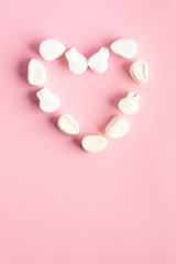 Fototapeta premium Sugar clouds making the shape of a heart on pink background