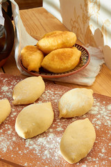Baked pies with cottage cheese and a number lie for baking, on the kitchen table under the bright rays of the sun.