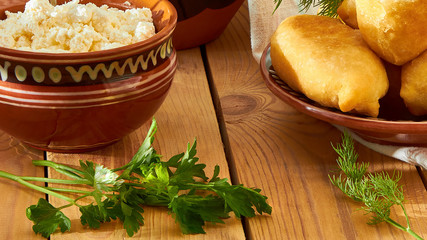 Baked pies with cottage cheese and dill, parsley, on the kitchen table in the morning.