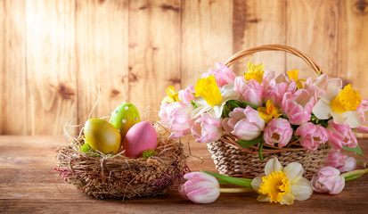 Easter holiday basket with beautiful spring flowers and nest with Easter eggs.
