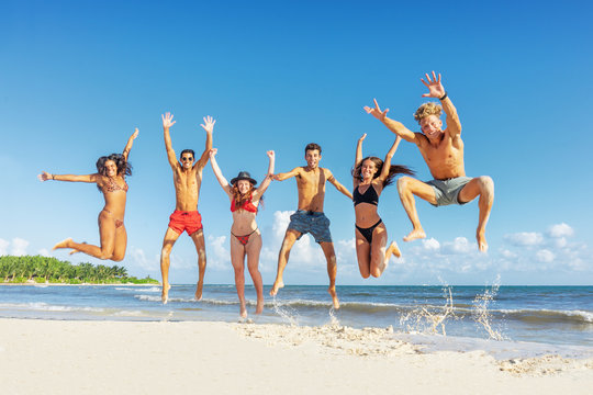 Happy group of young friends jumping at the beach