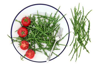 Samphire health food sea vegetable with tomatoes on a metal plate with old silver fork, high in antioxidants, fucoidans, dietary fiber and calcium. Salicornia europaea
