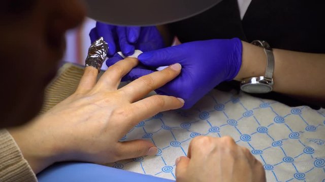 step of manicure process: nail gel polish removal using foil pieces.