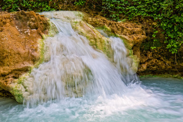 Natural hot springs - Fosso Bianco. The thermal water at Bagni San Filippo have created a  landscape of white limestone formations, waterfalls and small pools of warm water in forest, Tuscany, Italy