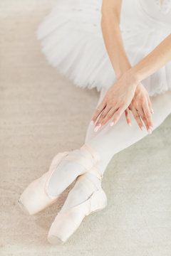 female dancer sitting on the floor with her legs crossed. close up cropped photo, final position in the performance, swan lake