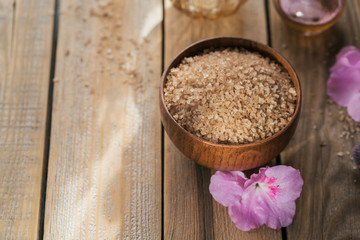 Sea salt, natural handmade soap, natural cosmetic oil and colorful towels with azalea flowers on rustic wooden background