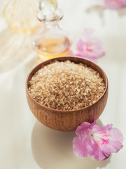 Sea salt, natural handmade soap, natural cosmetic oil and colorful towels with azalea flowers on rustic wooden background