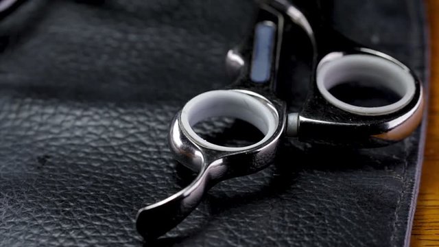 Zoom in on hair dressing scissors in a leather pouch. Professional hair salon tools used in a beauty or barbershop for grooming woman's hair. Modern professional beauty boutique. 