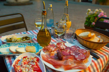 White wine and tasty italian homemade snack.Italian dinner table with homemade antipasti, cheese and ham, Pienza, Tuscany, Italy