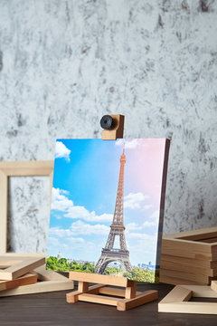 Photo of Paris printed on canvas, a wooden easel and stretcher bars on table