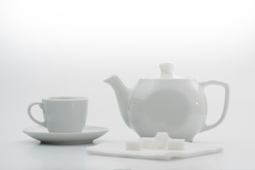 White teapot and white cup on a white background