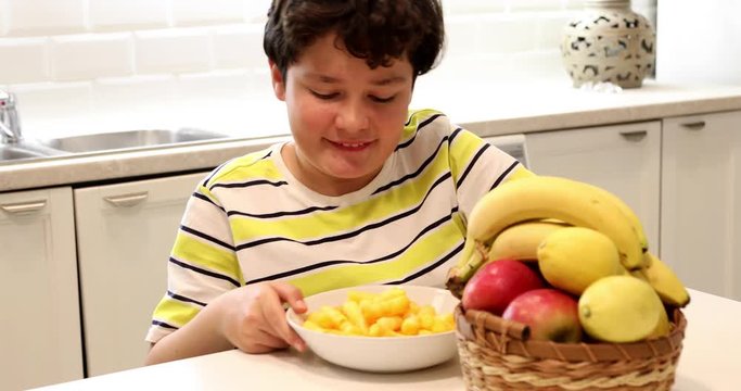 Teen boy choosing between fruits and chips