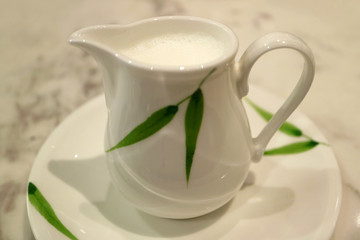 White with green leaf pattern milk pitcher on a saucer