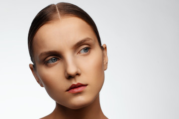 Close-up portrait of a beautiful model with clean makeup and collected hair, photographed in a photo studio