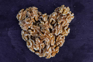 Walnuts, heart shaped, on black surface